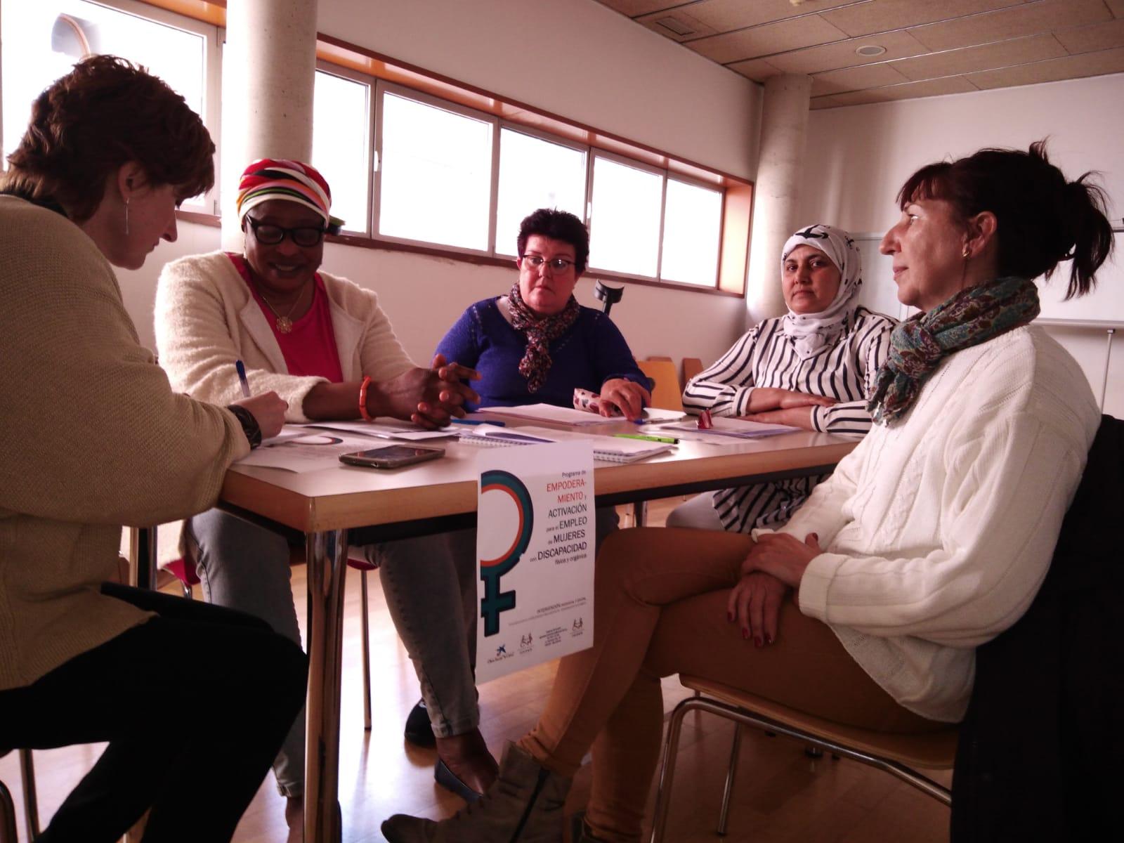 Un grup de dones, segudes al voltant d'una taula, durant una de les intervencions grupals. Imatge d'un grup de dones participant en una de les sessions de grup.